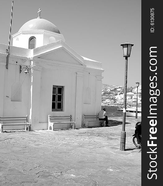 A black and white image of a man backed to a Greek church in Mykonos, Greece. A black and white image of a man backed to a Greek church in Mykonos, Greece.