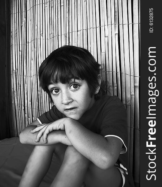 The child sitting alone - the photo is in black and white. The child sitting alone - the photo is in black and white