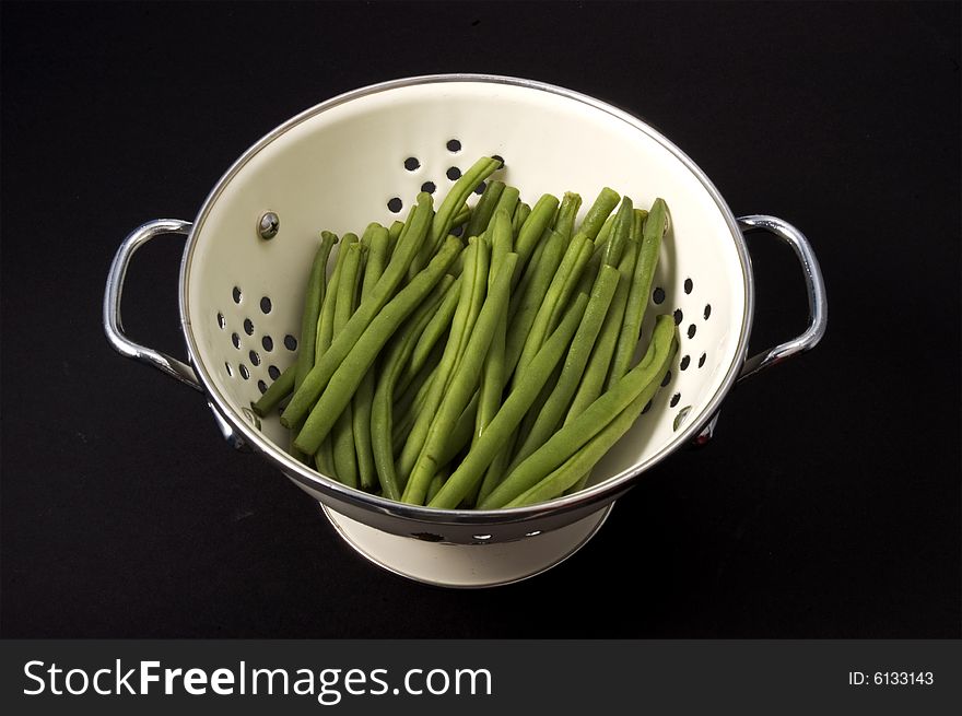 Kitchen colander filled with green beans brightly lit on isolated white background. Kitchen colander filled with green beans brightly lit on isolated white background