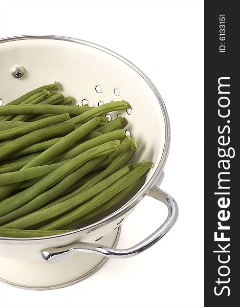 Kitchen colander filled with green beans brightly lit on isolated white background. Kitchen colander filled with green beans brightly lit on isolated white background