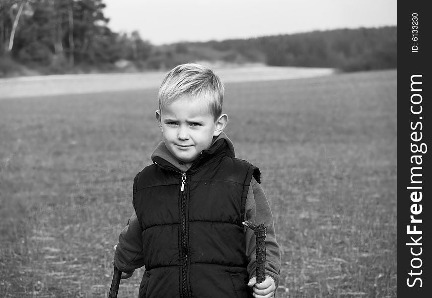 The small boy is playing in the meadow - the photo is in black and white. The small boy is playing in the meadow - the photo is in black and white