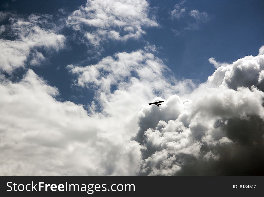 An airplane flying in the blue cloudy sky, horizontal image. An airplane flying in the blue cloudy sky, horizontal image