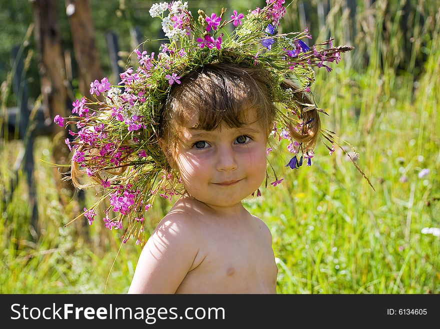 The little girl in wildflower diadem modestly smiles. The little girl in wildflower diadem modestly smiles