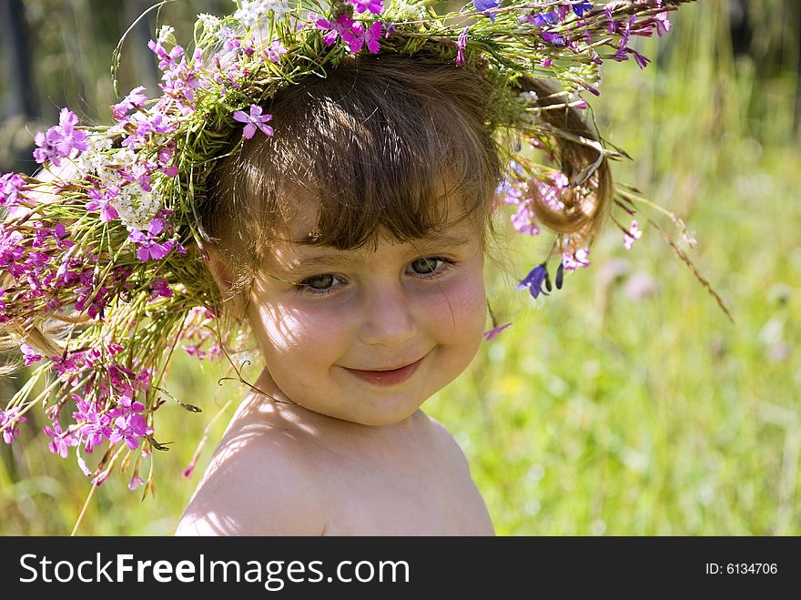 The little girl in wildflower diadem modestly smiles. The little girl in wildflower diadem modestly smiles