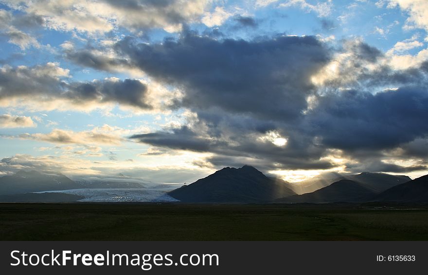 Sunset behind the clouds and a valley filled by a glacier. Sunset behind the clouds and a valley filled by a glacier.