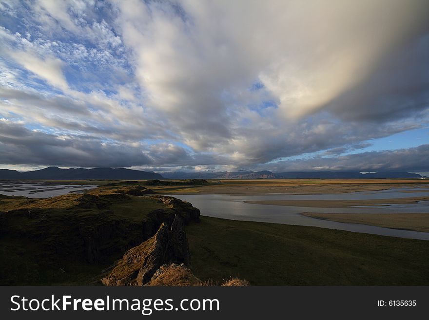 Dramatically cloudy sky reflecting in shallow waters of the flooded flats lit by the setting sun. Dramatically cloudy sky reflecting in shallow waters of the flooded flats lit by the setting sun.