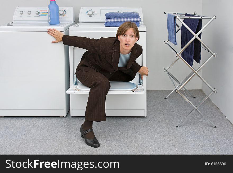 Woman in business suit climbs out of a clothes dryer. Metaphor for the emergence of women and mothers into the business world. Woman in business suit climbs out of a clothes dryer. Metaphor for the emergence of women and mothers into the business world.