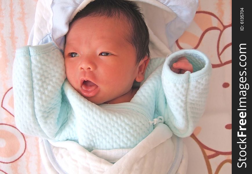 A Chinese baby on a bed, opening her mouth. A Chinese baby on a bed, opening her mouth