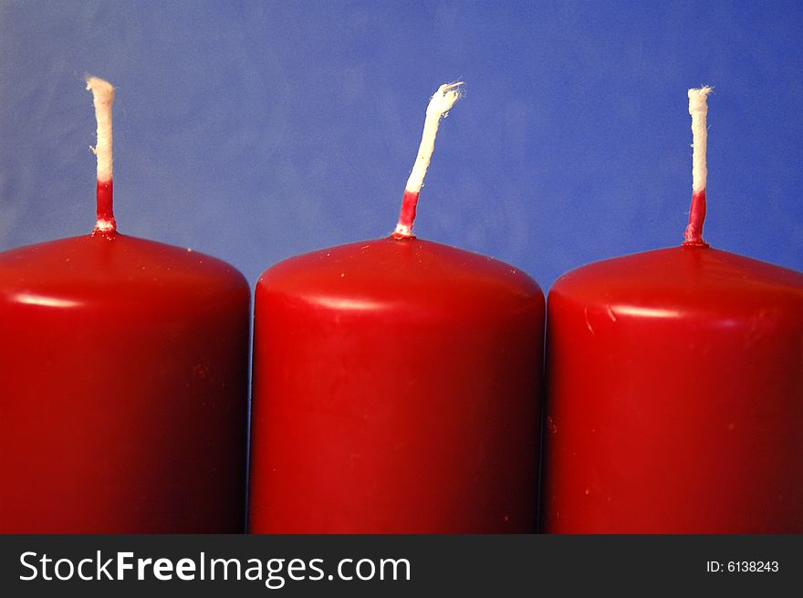 Set of three red candles over teh blue background. Set of three red candles over teh blue background