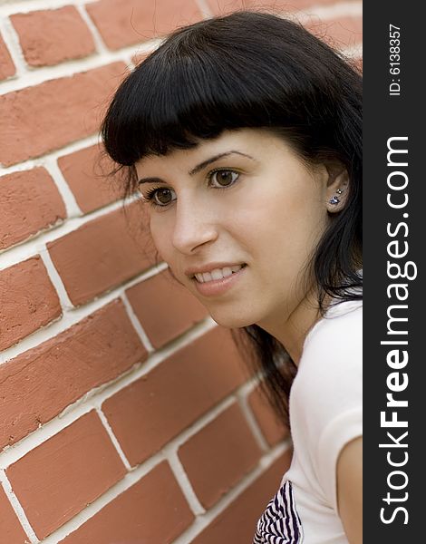 Closeup portrait of young pretty brunet girl against brick wall