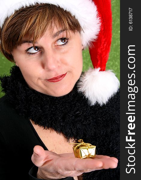 Mature lady wearing a christmas hat holding a small gift. Mature lady wearing a christmas hat holding a small gift