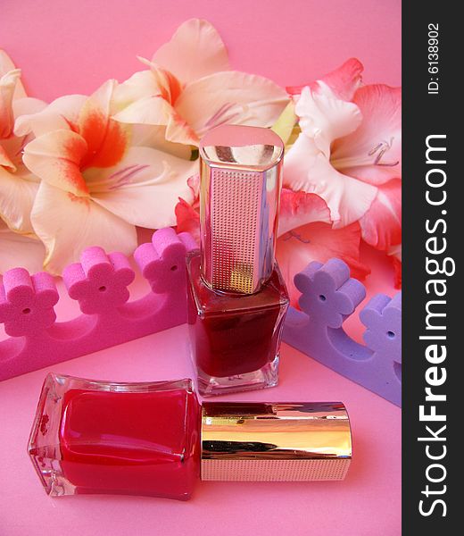 Two nail polish on pink background and flowers around