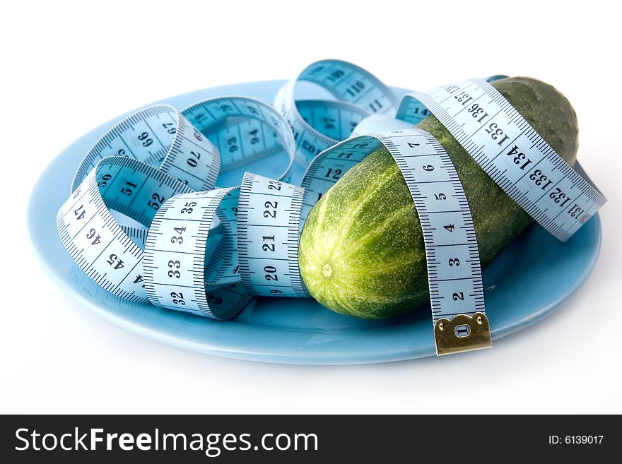 Green fresh cucumber bound with tape measure on a blue plate. Green fresh cucumber bound with tape measure on a blue plate