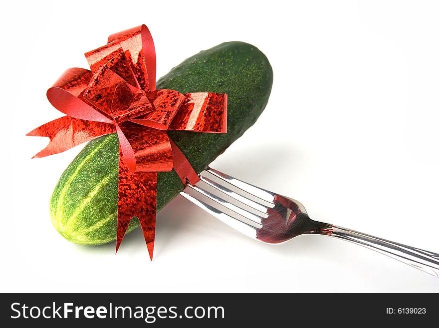 Green fresh cucumber bound with red bow stabbed on a fork. Green fresh cucumber bound with red bow stabbed on a fork