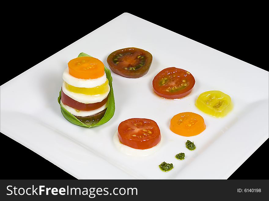 Caprese salad of five heirloom tomatoes on a white plate