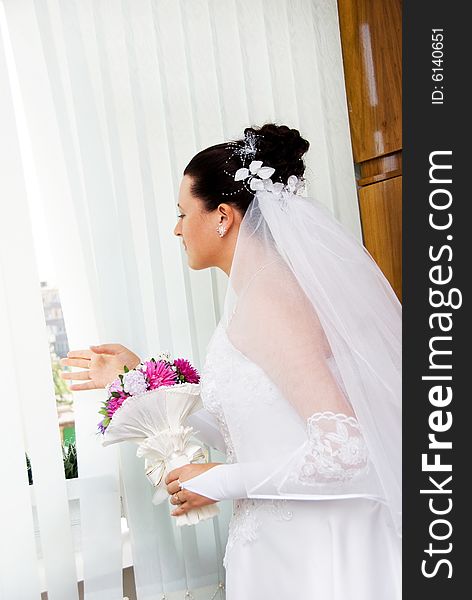 Bride waits for the groom and looks out of the window. Bride waits for the groom and looks out of the window