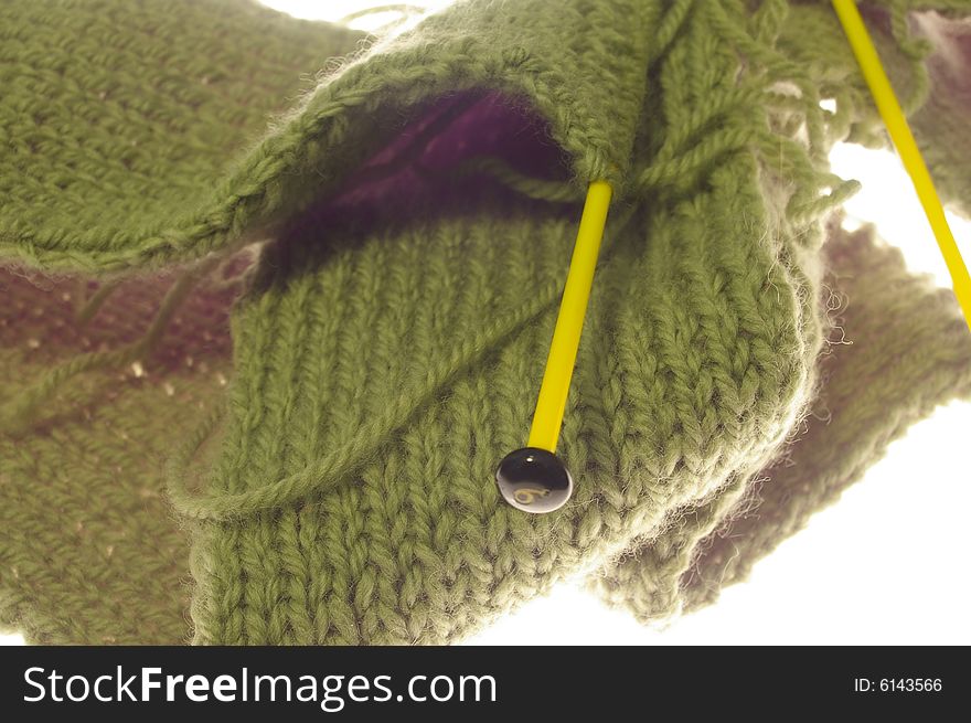 Unfinished green knitted scarf with yellow knitting needles, isolated on a while background. Unfinished green knitted scarf with yellow knitting needles, isolated on a while background