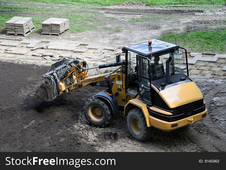 Construction Vehicle. Green grass and black earth in the background. Construction Vehicle. Green grass and black earth in the background