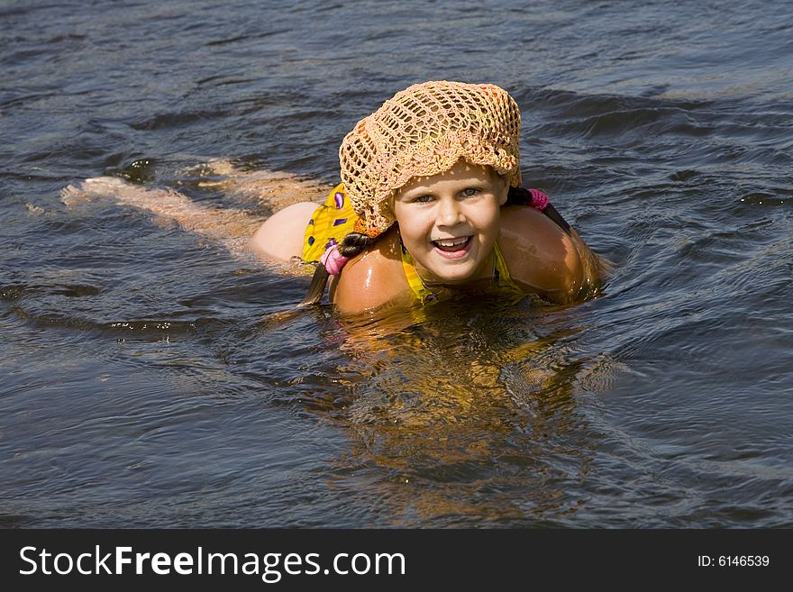 Little girl in orange hat swimming in a river in the summer. Little girl in orange hat swimming in a river in the summer