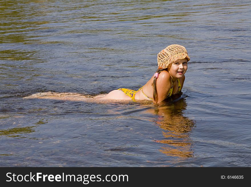 Little girl in orange hat swimming in a river in the summer. Little girl in orange hat swimming in a river in the summer