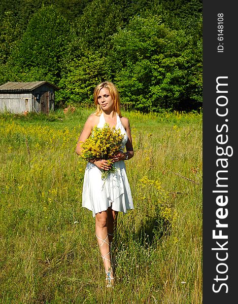 Blond woman in white dress walking through the meadow