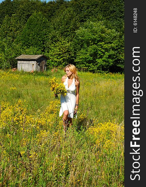 Blond woman in white dress walking through the meadow. Blond woman in white dress walking through the meadow