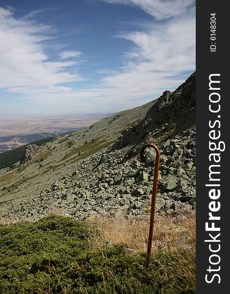 A cane is planted in the ground, beyond it can be seen a high mountain panorama. A cane is planted in the ground, beyond it can be seen a high mountain panorama