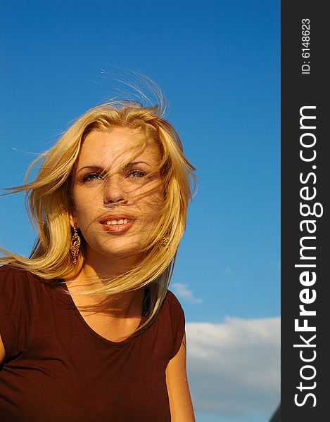 Blond woman with fly-away hair against blue sky. Blond woman with fly-away hair against blue sky