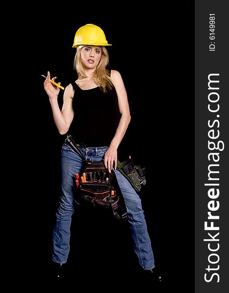 Sexy blond female construction worker with hard hat and tool pouch on black background