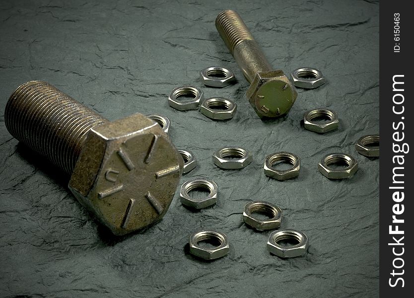 Brass nuts and bolts on textured surface. Brass nuts and bolts on textured surface