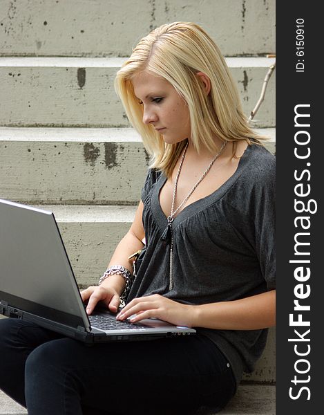 Young, blonde girl with laptop sits on a staircase. Young, blonde girl with laptop sits on a staircase.