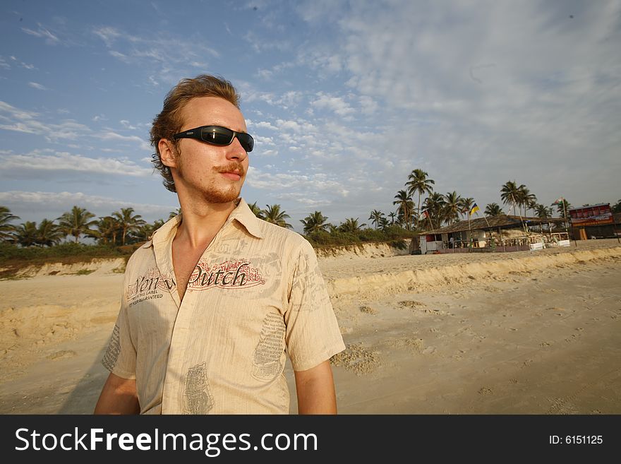 Young man spectacle on a beach looks in the sunshine