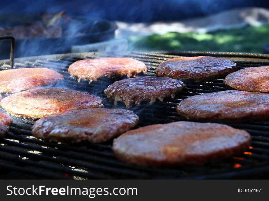 Set of Hamburger patties sitting on a flamed charcoal grill. Set of Hamburger patties sitting on a flamed charcoal grill.