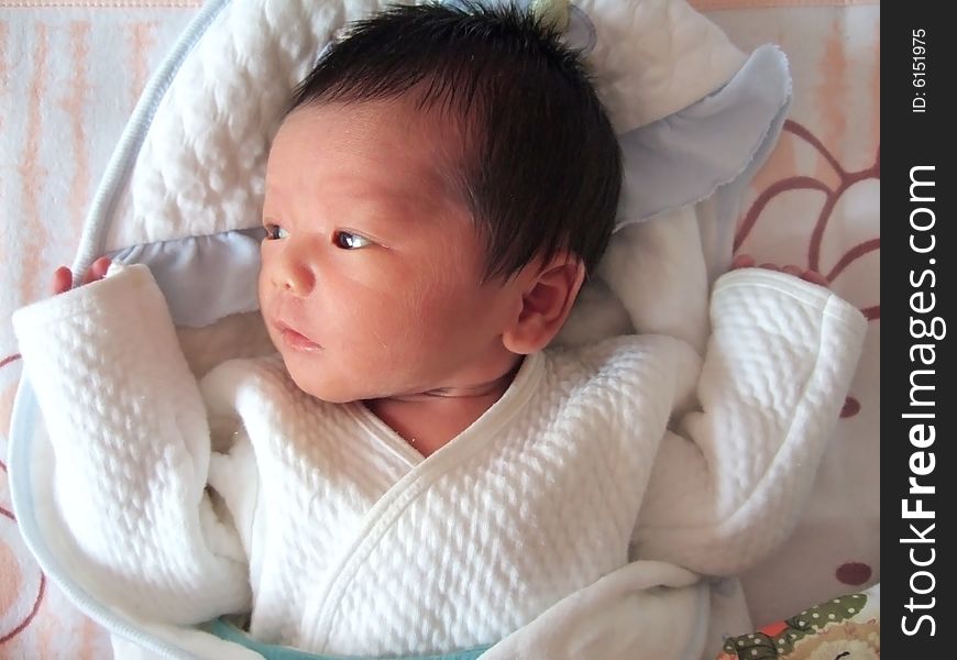 Lovely baby in white on a bed