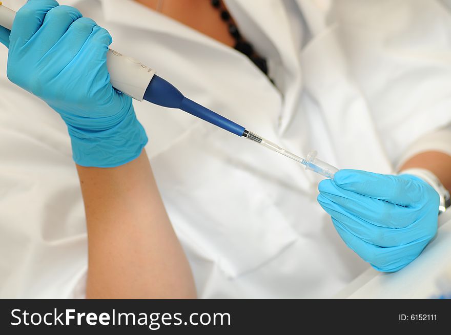 Researcher is pipetting, while protected with lab coat and gloves.