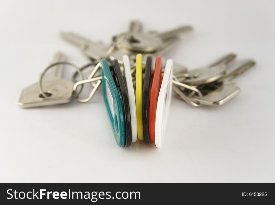 Vertically placed green, white, yellow, red and black key chains with text labels and keys. Focus is on the key fobs.