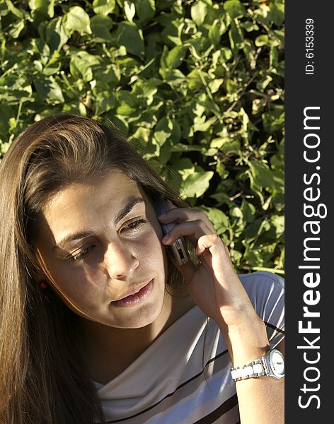 Young teen girl talking on cell phone in garden. Young teen girl talking on cell phone in garden