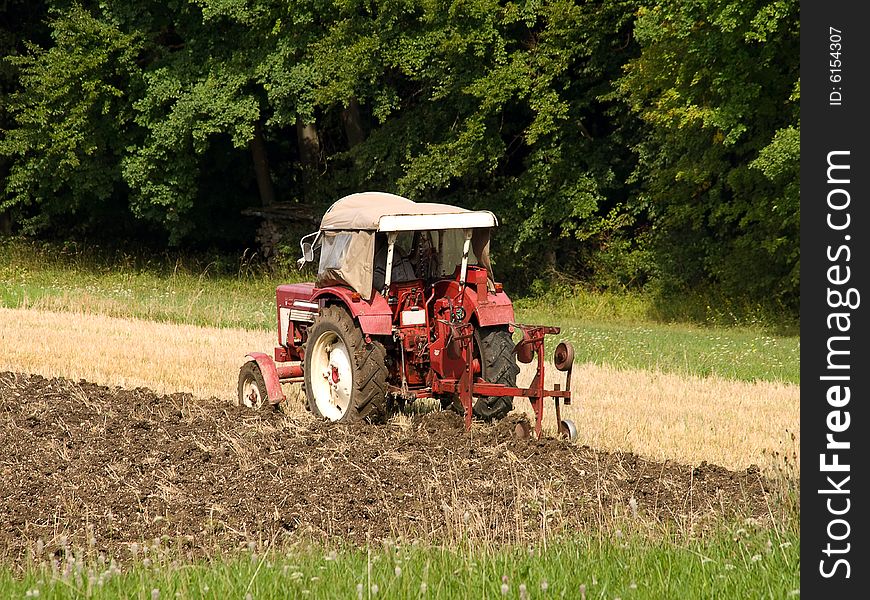 Red tractor plowing a field in the summer. Red tractor plowing a field in the summer