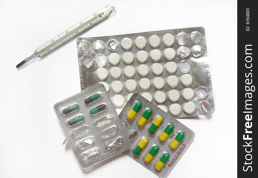A photograph of some pills and thermometer. Health concept