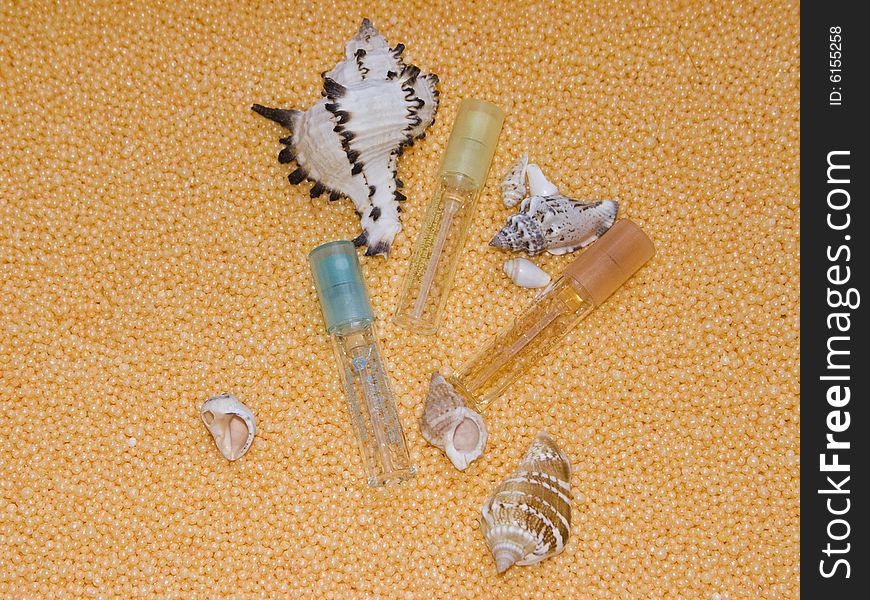 The image of bottles of perfume and cockleshells on a yellow background. The image of bottles of perfume and cockleshells on a yellow background