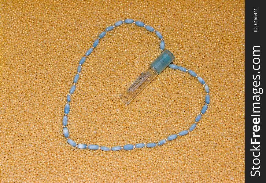The image of heart from a thread of a beads and a bottle of perfume. The image of heart from a thread of a beads and a bottle of perfume