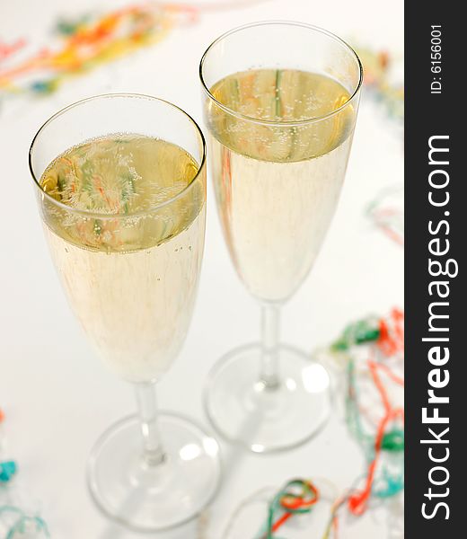 Two Champagne flute glasses with Champagne with party streamers at base. Two Champagne flute glasses with Champagne with party streamers at base