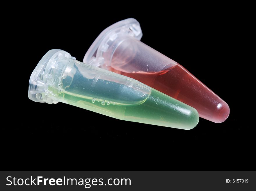 Eppendorf vials with red and green liquid isolated on black background