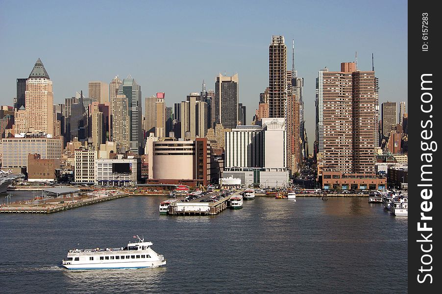 The evening view of the water transport boat passing by and Manhattan landmark with a straight street where you can see the other side of the island (New York City). The evening view of the water transport boat passing by and Manhattan landmark with a straight street where you can see the other side of the island (New York City).