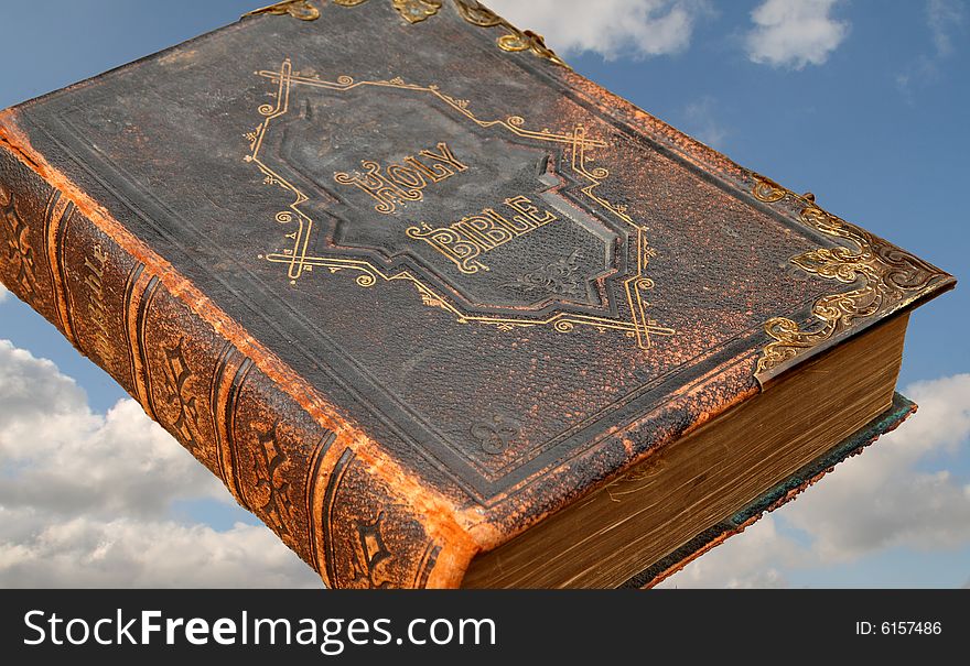 Isolated image of an ancient leather bound Holy Bible with Brass inlays against the backdrop of a Heavenly Blue Sky. Isolated image of an ancient leather bound Holy Bible with Brass inlays against the backdrop of a Heavenly Blue Sky