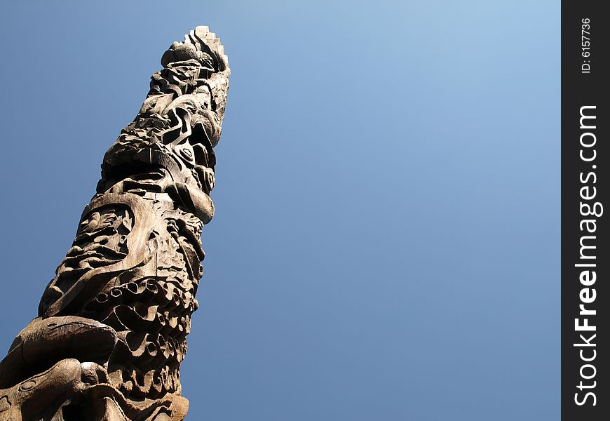 A carved wooden totem pole on a clear day.