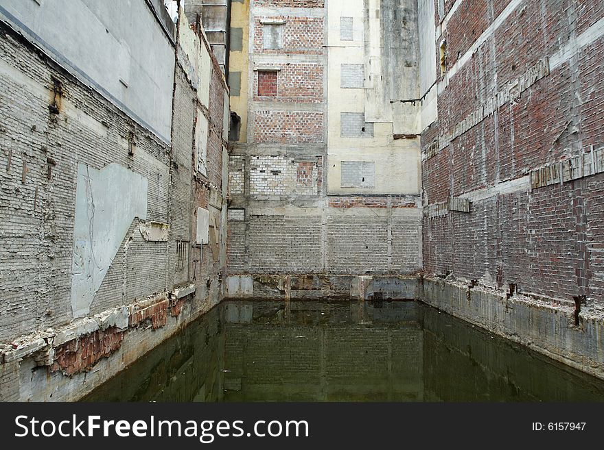 Three brick walls with a pool of murky water below. Three brick walls with a pool of murky water below