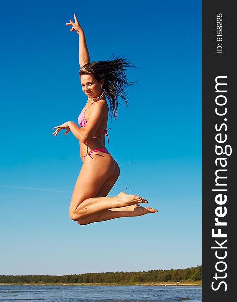Woman in pink bikini jumps high on a beach. Woman in pink bikini jumps high on a beach