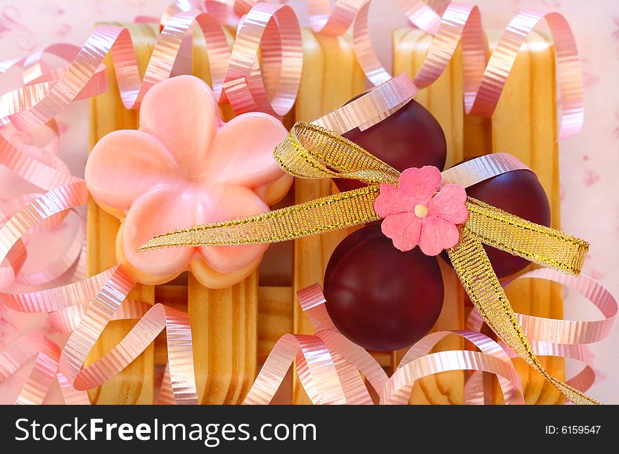 Pretty soap and bath beads on a wooden soap tray surrounded by pink ribbons. Pretty soap and bath beads on a wooden soap tray surrounded by pink ribbons.