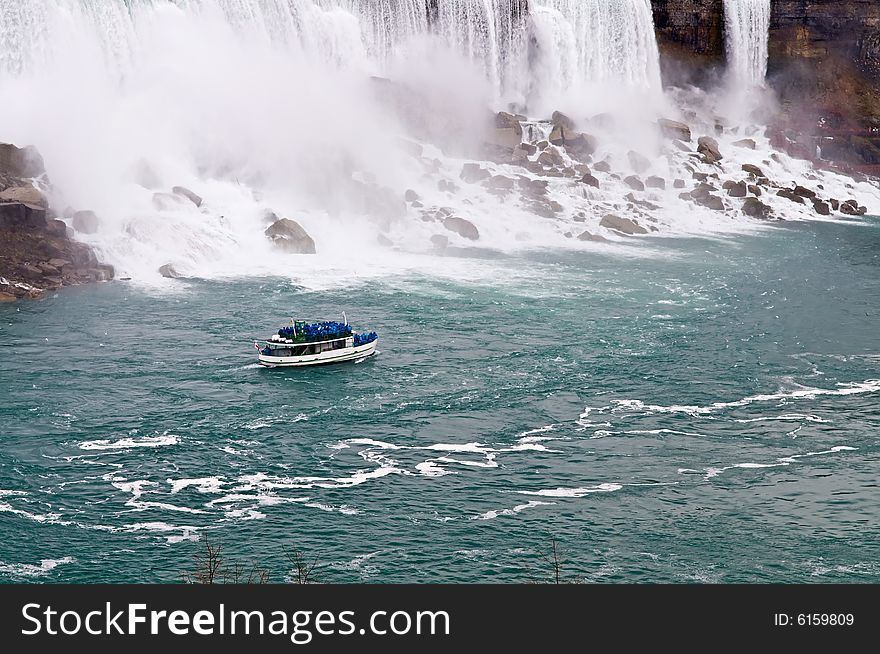 A boat sailing in a river next to Niagara falls. A boat sailing in a river next to Niagara falls